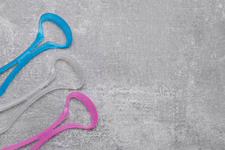 Tongue cleaners on gray table, flat lay. Space for textの写真素材