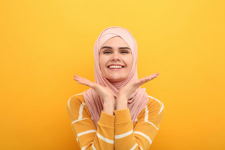 Portrait of Muslim woman in hijab on orange backgroundの写真素材