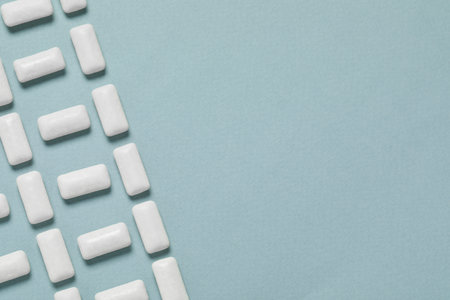 Tasty white chewing gums on light blue background, flat lay. Space for textの写真素材