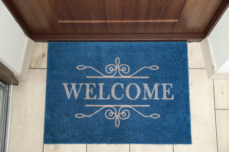 Beautiful blue doormat with the word Welcome on floor near entrance, top viewの写真素材