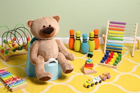 Teddy bear on light blue baby potty and many other toys indoors. Toilet trainingの写真素材