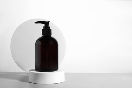 Bottle of cosmetic product and podiums on light gray table against white background, space for textの写真素材