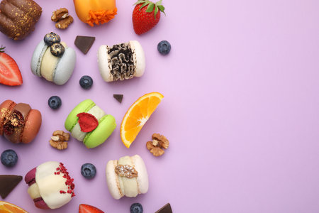 Delicious macarons, oranges and berries on violet table, flat lay. Space for textの写真素材