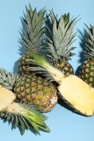 Whole and cut ripe pineapples on light blue backgroundの写真素材