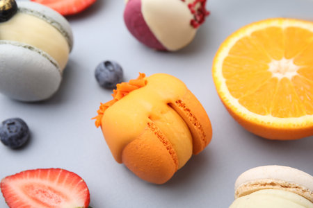 Delicious macarons, fruits and berries on light blue table, closeupの写真素材