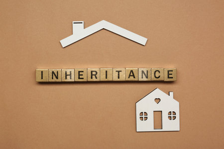 Word Inheritance made with wooden cubes and house model on brown background, flat layの写真素材