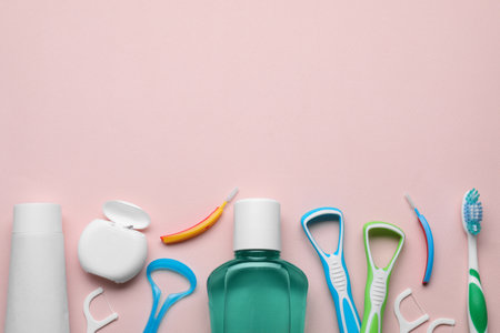 Tongue cleaners and other oral care products on pink background, flat lay. Space for textの写真素材