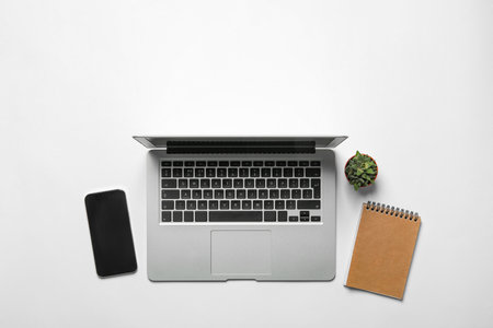 Laptop, smartphone, notebook and houseplant on white background, flat lay. Space for textの写真素材