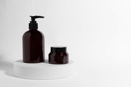 Bottle and jar with cosmetic products on white background, space for textの写真素材
