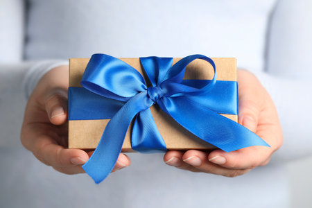 Woman holding gift box with blue bow, closeupの写真素材