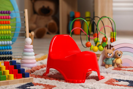 Red baby potty and toys on carpet in room. Toilet trainingの写真素材