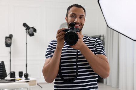 Young professional photographer with camera in modern photo studio, space for textの写真素材