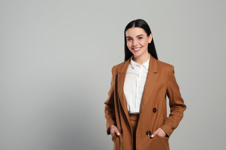 Beautiful real estate agent in nice suit on gray background, space for textの写真素材