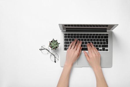 Woman using laptop at white table, top view. Space for textの写真素材
