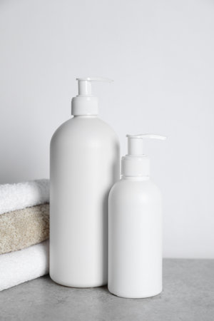Bottles of cosmetic products and towels on gray tableの写真素材