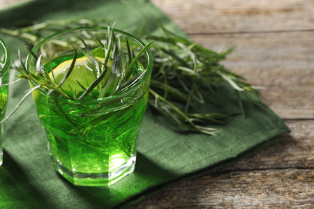 Glass of refreshing tarragon drink with lemon slice on wooden table. Space for textの写真素材