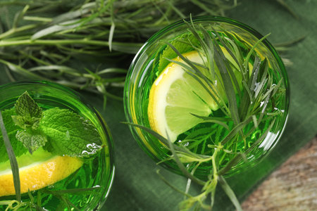 Glasses of refreshing tarragon drink with lemon slices on table, flat layの写真素材