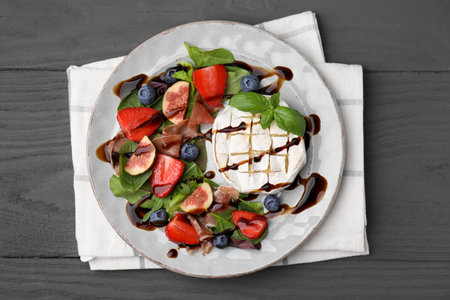 Delicious salad with brie cheese, prosciutto, berries and balsamic vinegar on gray wooden table, top viewの写真素材