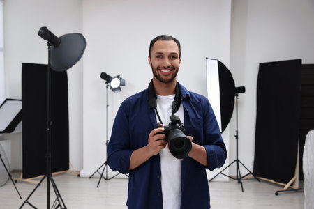Young professional photographer with camera in modern photo studioの写真素材