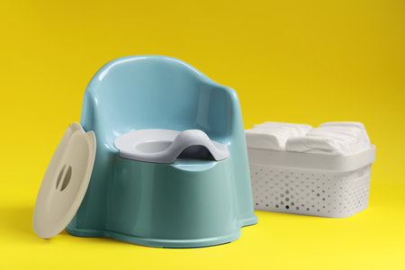 Light blue baby potty and diapers on yellow background. Toilet trainingの写真素材