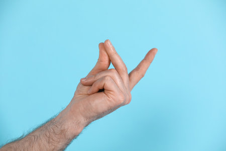Man snapping his fingers on light blue background, closeup. Bad habitの写真素材