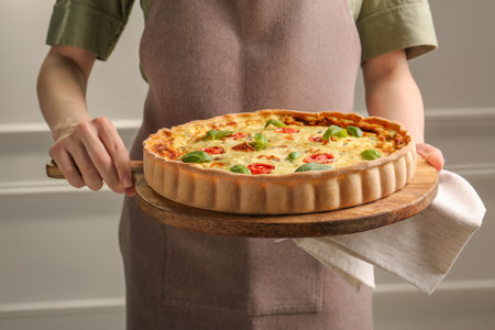Woman with delicious homemade cheese quiche indoors, closeup