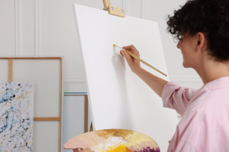 Young woman painting on easel with canvas in studioの写真素材