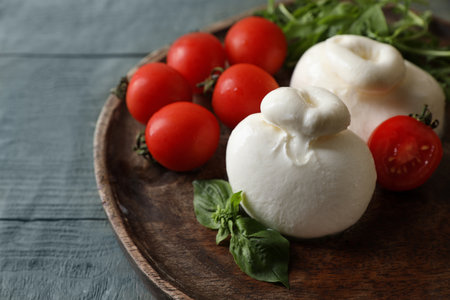Delicious burrata cheese with tomatoes on gray wooden table, closeup. Space for textの写真素材