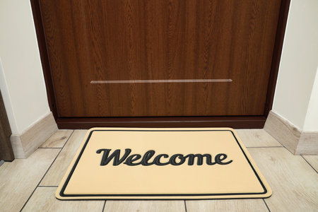 Beautiful beige doormat with the word Welcome on floor near entranceの写真素材