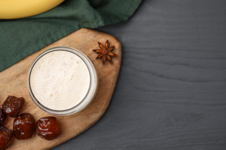 Glass of delicious date smoothie, dried fruits and anise on gray wooden table, flat lay. Space for textの写真素材