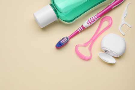 Tongue cleaner and other oral care products on beige background, flat lay. Space for textの写真素材