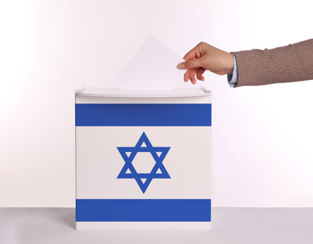 Woman putting her vote into ballot box decorated with flag of Israel against white background, closeupの写真素材