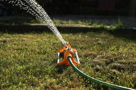 Automatic sprinkler watering green grass on sunny day outdoors. Irrigation systemの写真素材