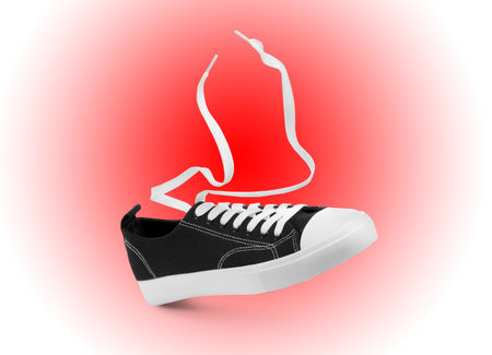 One stylish sneaker in air on red gradient backgroundの写真素材