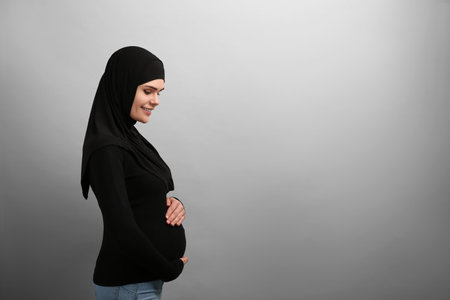 Portrait of pregnant Muslim woman in hijab on light gray background, space for textの写真素材