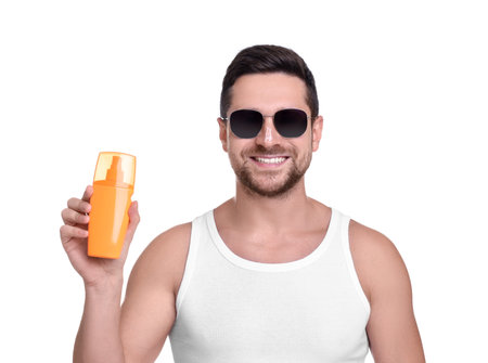 Handsome man in sunglasses holding bottle of sun protection cream on white backgroundの写真素材