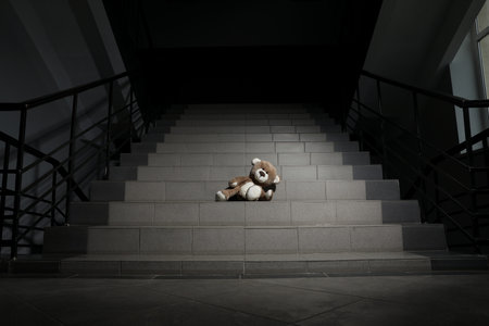 Lonely teddy bear on gray stairs indoorsの写真素材