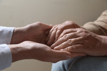 Woman holding hands with her mother on beige background, closeupの写真素材