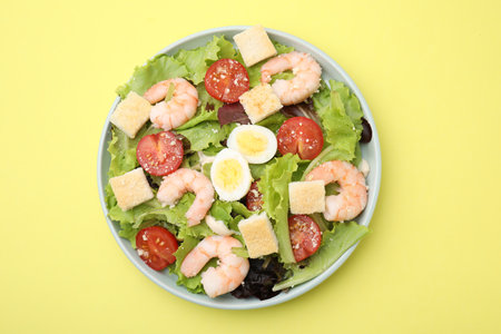 Delicious Caesar salad with shrimps on yellow background, top viewの写真素材