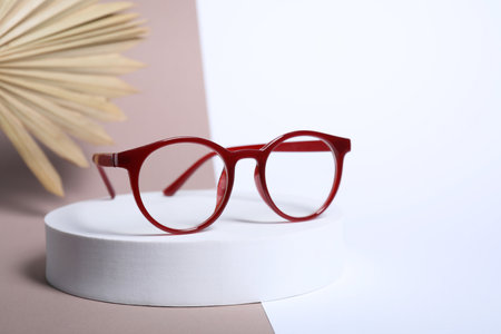 Stylish presentation of glasses with red frame on color background
