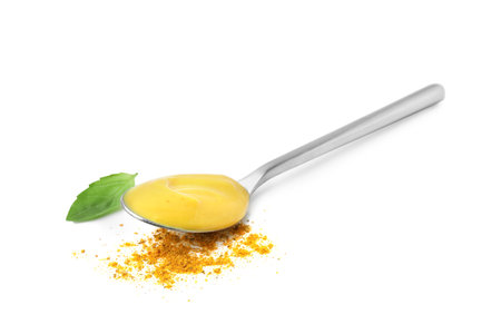 Spoon with tasty curry sauce, powder and basil leaf isolated on whiteの写真素材