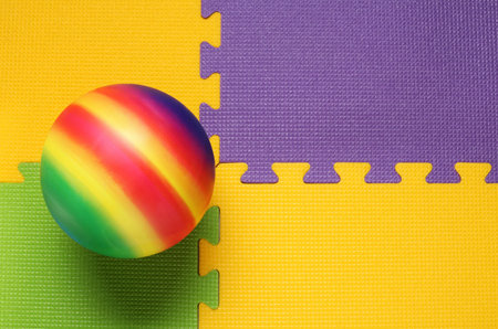 New bright kids' ball on puzzle mat, top view. Space for textの写真素材
