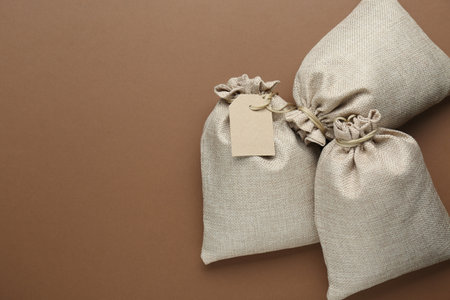 Tied burlap bags on brown background, flat lay. Space for textの写真素材