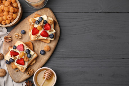 Tasty brie cheese sandwiches on gray wooden table, flat lay. Space for text
