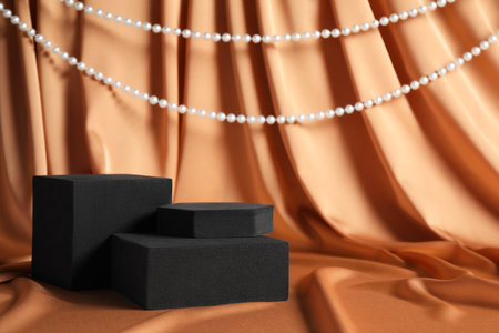 Black geometric figures and pearls on light brown fabric, space for text. Stylish presentation for productの写真素材