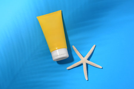 Sunscreen and starfish on light blue background, flat lay. Sun protection care