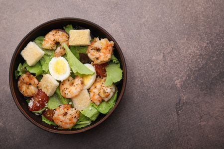 Delicious Caesar salad with shrimps on brown table, top view. Space for textの写真素材