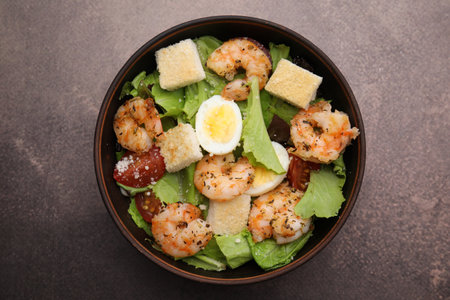 Delicious Caesar salad with shrimps on brown table, top viewの写真素材
