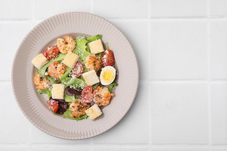 Delicious Caesar salad with shrimps on white tiled table, top view. Space for textの写真素材