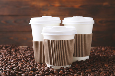 Coffee to go. Paper cups on roasted beans, closeupの写真素材